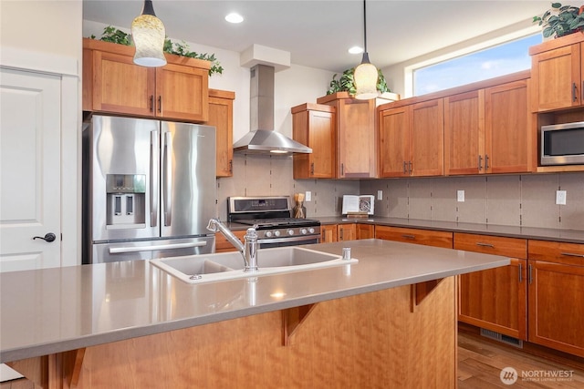 kitchen with a sink, tasteful backsplash, appliances with stainless steel finishes, a breakfast bar area, and wall chimney range hood