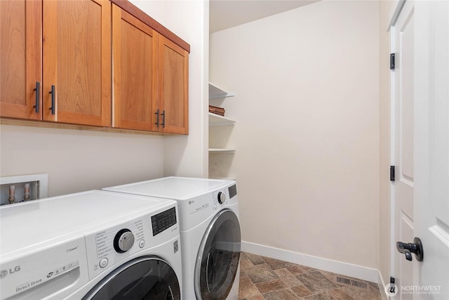 laundry area featuring visible vents, stone finish flooring, baseboards, washer and dryer, and cabinet space