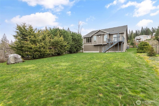 rear view of house featuring stairway, a lawn, and a wooden deck