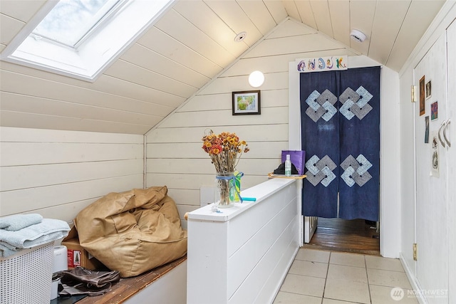 interior space with wooden ceiling, vaulted ceiling with skylight, and light tile patterned floors