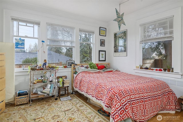 bedroom with crown molding and wood finished floors