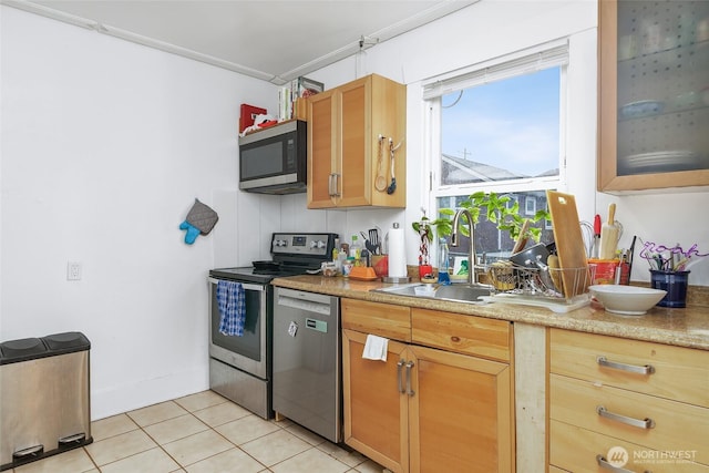 kitchen with light countertops, light tile patterned floors, appliances with stainless steel finishes, and a sink