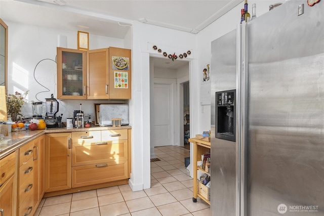 kitchen with light tile patterned floors, stainless steel fridge, tasteful backsplash, and glass insert cabinets