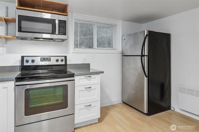 kitchen with light wood-type flooring, open shelves, radiator heating unit, stainless steel appliances, and white cabinets