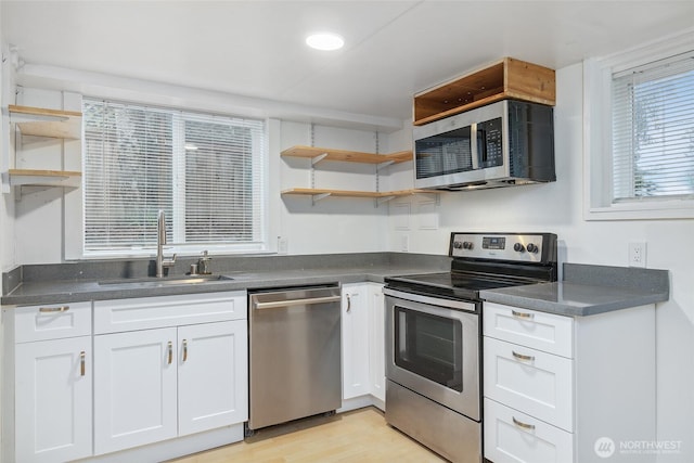 kitchen with open shelves, dark countertops, appliances with stainless steel finishes, and a sink