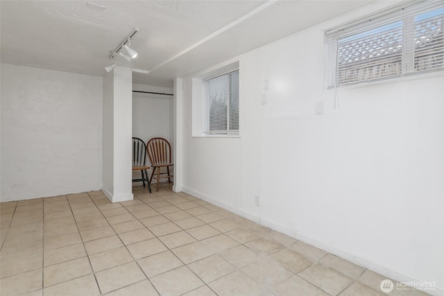 unfurnished room with light tile patterned floors, baseboards, and rail lighting