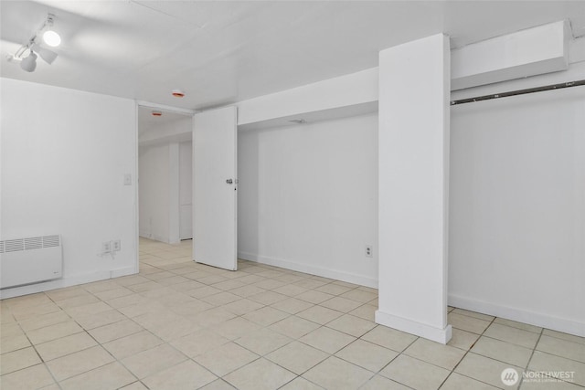 finished below grade area featuring light tile patterned floors, baseboards, and radiator heating unit