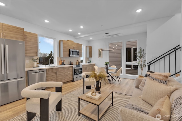 living area with recessed lighting, light wood-style flooring, and stairs