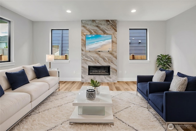 living room with wood finished floors, recessed lighting, a high end fireplace, and baseboards