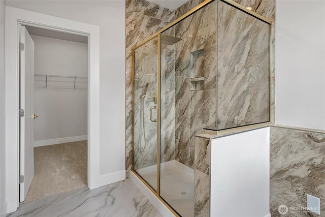 full bath with a marble finish shower, a spacious closet, and marble finish flooring