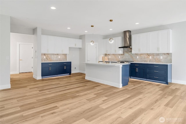 kitchen featuring wall chimney exhaust hood, blue cabinets, tasteful backsplash, white cabinetry, and light countertops