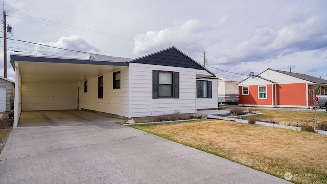 view of front facade featuring concrete driveway, a carport, and a front yard