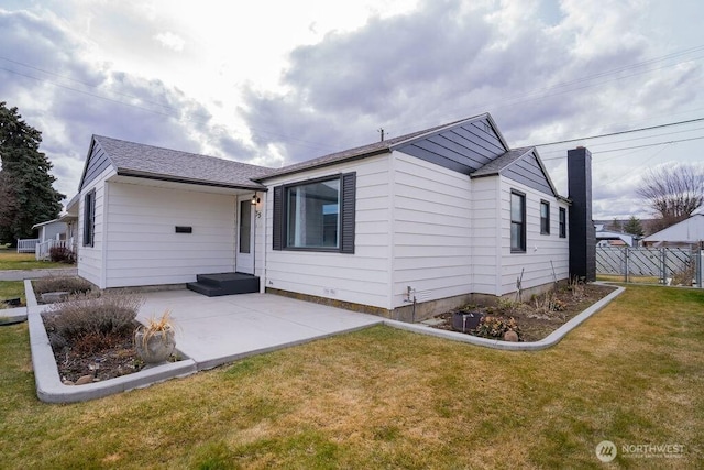 back of house featuring a patio area, roof with shingles, a yard, and fence