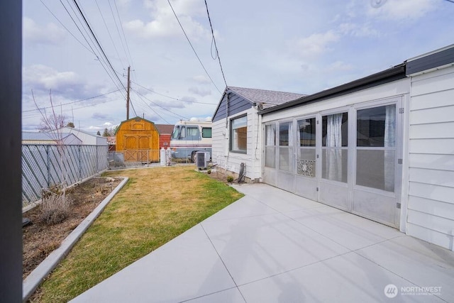 view of yard featuring an outbuilding, a shed, a patio area, and fence