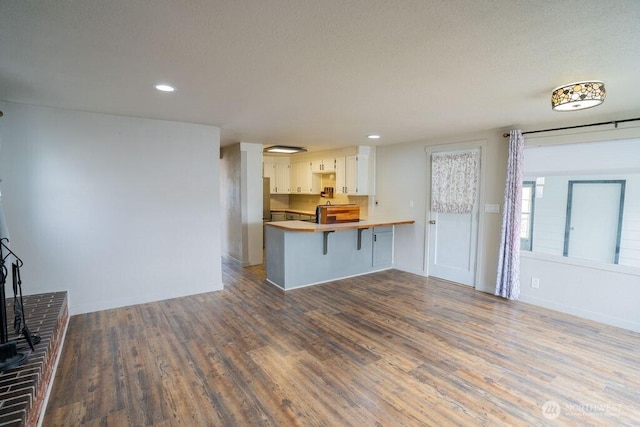 unfurnished living room featuring recessed lighting, a textured ceiling, baseboards, and wood finished floors