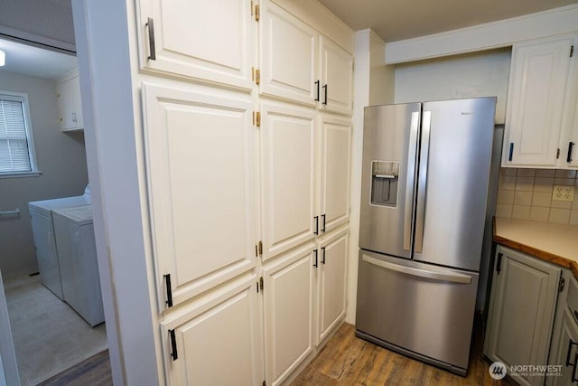 kitchen featuring washer and clothes dryer, backsplash, wood finished floors, stainless steel fridge with ice dispenser, and light countertops