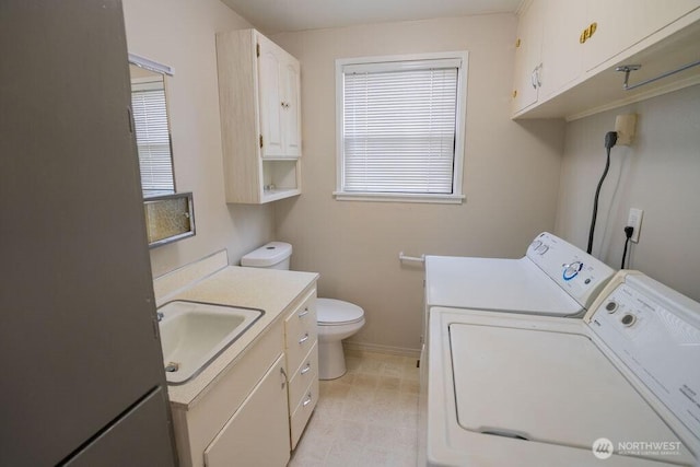 washroom with laundry area, baseboards, independent washer and dryer, and a sink