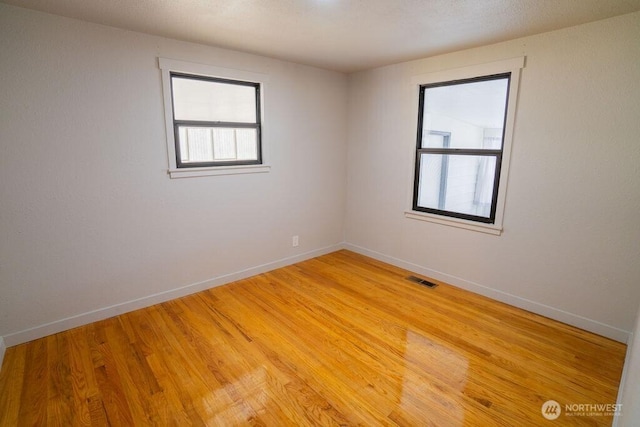 empty room with visible vents, baseboards, and light wood-style floors