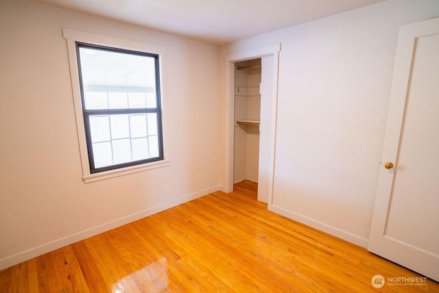 unfurnished bedroom featuring light wood-style flooring, baseboards, and a closet