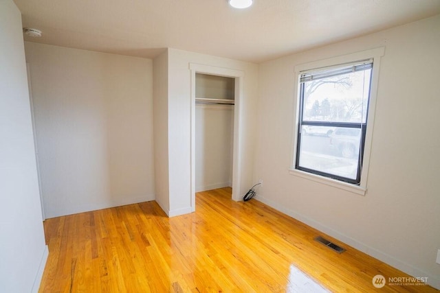 unfurnished bedroom with visible vents, baseboards, a closet, and light wood finished floors