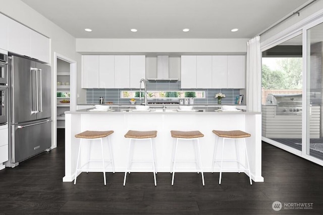 kitchen featuring a kitchen bar, light countertops, modern cabinets, and appliances with stainless steel finishes