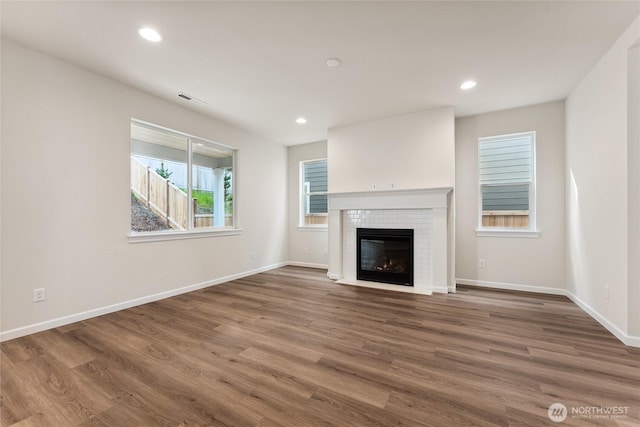 unfurnished living room with visible vents, wood finished floors, recessed lighting, a fireplace, and baseboards