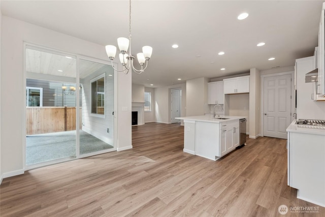 kitchen featuring a sink, light countertops, white cabinetry, open floor plan, and a chandelier