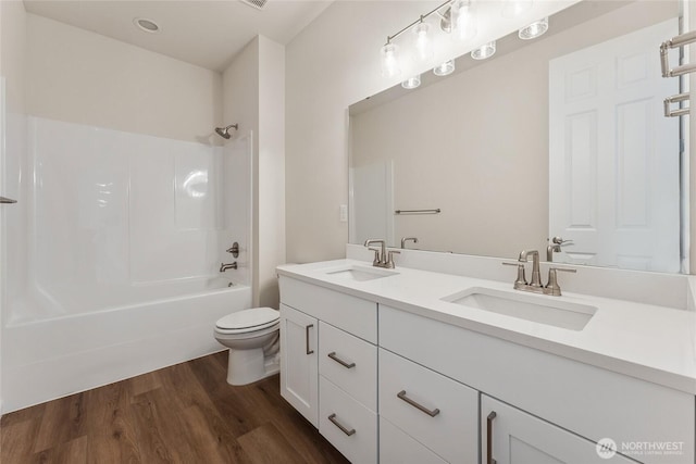 full bathroom featuring double vanity, toilet, wood finished floors, and a sink