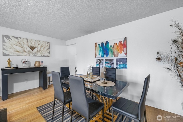 dining space featuring a textured ceiling and wood finished floors