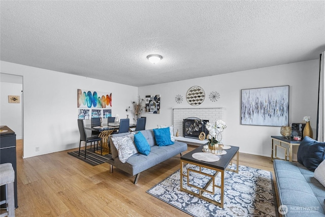 living room featuring a fireplace, a textured ceiling, and light wood-type flooring