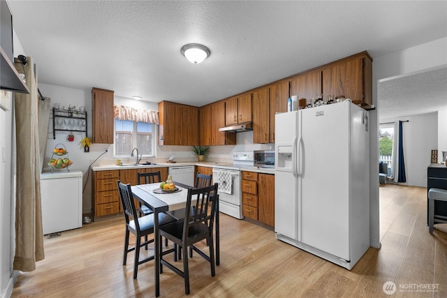 kitchen with brown cabinetry, white appliances, and light wood-style floors