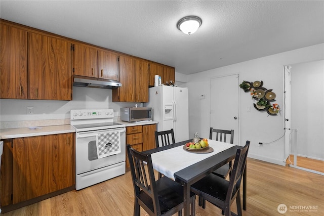 kitchen featuring white appliances, brown cabinetry, light wood-style flooring, light countertops, and under cabinet range hood