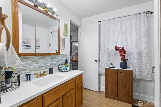 bathroom with decorative backsplash, vanity, and wood finished floors