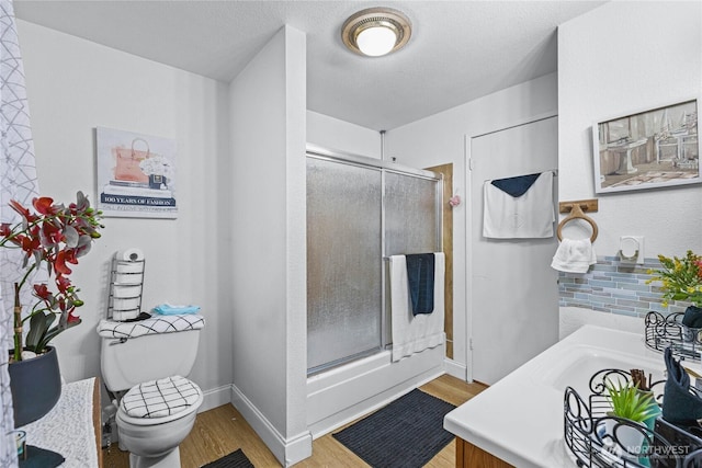 full bathroom featuring a shower stall, toilet, wood finished floors, and baseboards