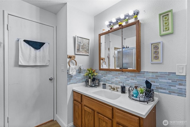 bathroom with tasteful backsplash, a stall shower, and vanity