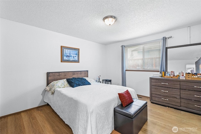 bedroom featuring baseboards, a textured ceiling, and light wood-style floors