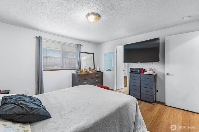 bedroom with light wood-style floors and a textured ceiling