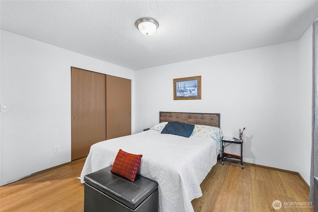 bedroom with light wood-style floors, a closet, and a textured ceiling