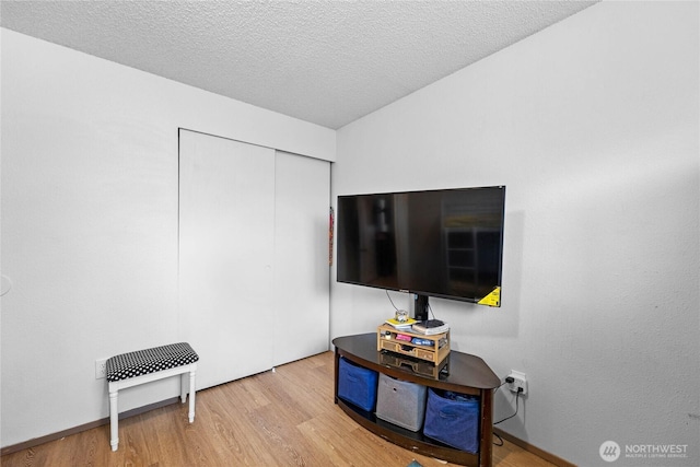 rec room featuring light wood-style flooring and a textured ceiling