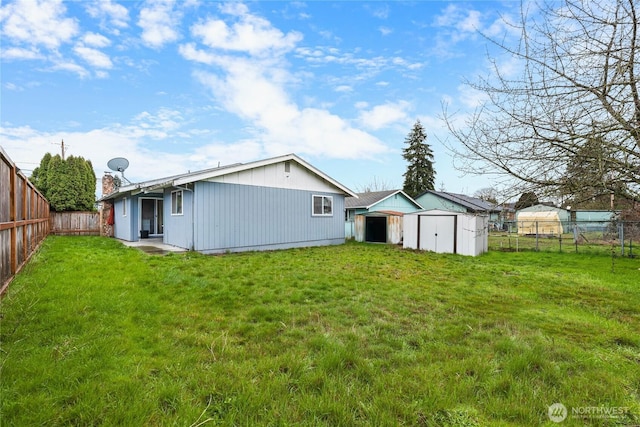 rear view of house with a lawn, a fenced backyard, a storage shed, and an outdoor structure