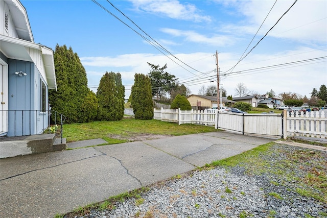 view of yard featuring a gate, fence, and driveway