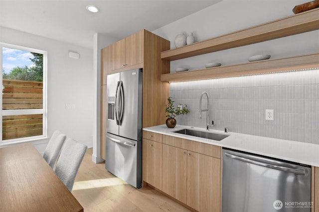 kitchen featuring open shelves, a sink, decorative backsplash, light countertops, and appliances with stainless steel finishes