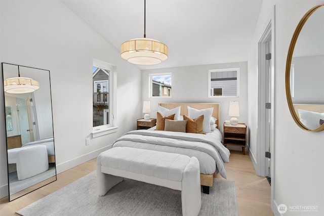 bedroom with light wood-style flooring, baseboards, and lofted ceiling