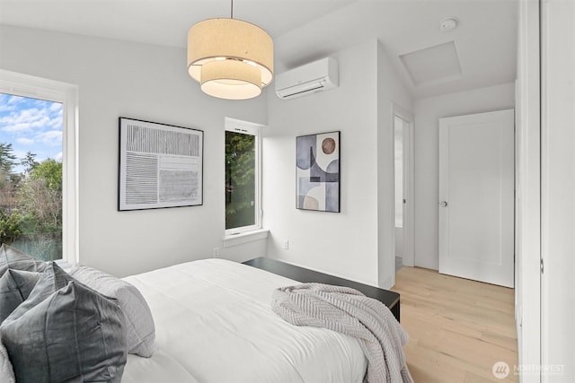 bedroom with attic access, a wall mounted air conditioner, and light wood-type flooring