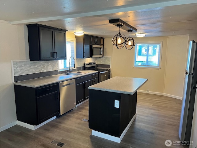 kitchen with visible vents, a sink, wood finished floors, appliances with stainless steel finishes, and decorative backsplash