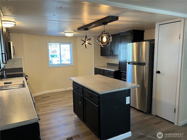 kitchen featuring appliances with stainless steel finishes, wood finished floors, light countertops, and dark cabinets