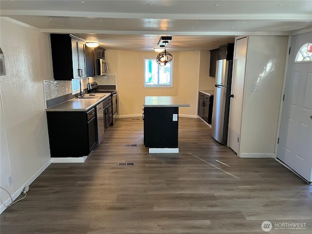 kitchen with dark wood-style floors, backsplash, appliances with stainless steel finishes, and a kitchen island