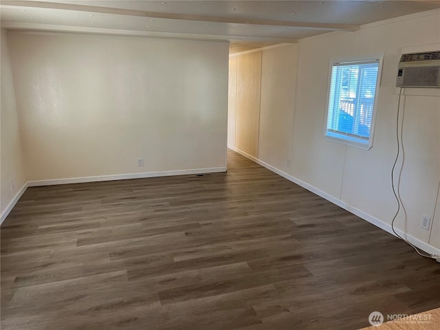 spare room with dark wood-type flooring, an AC wall unit, and baseboards