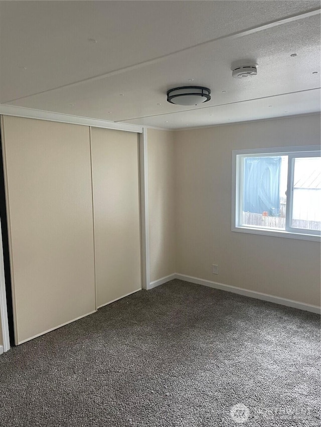 empty room with baseboards, carpet floors, and a textured ceiling