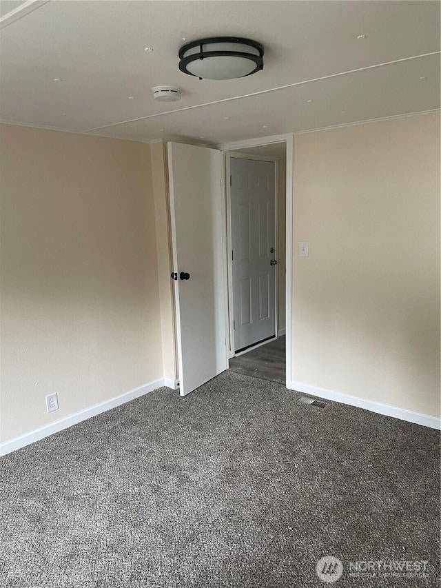 spare room with dark colored carpet and baseboards